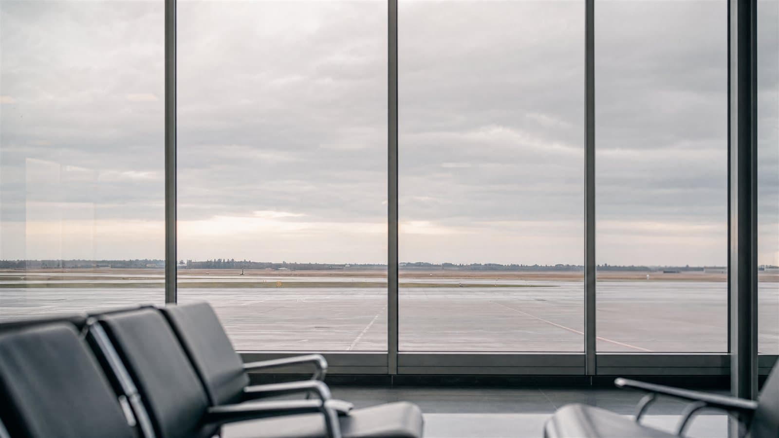공항 출국장 유리창 너머로 보이는 활주로와 흐린 하늘 — 국제이혼은 어디서 어느 법으로 할 것인지가 먼저 정해져야 재산과 양육의 이야기가 시작됩니다